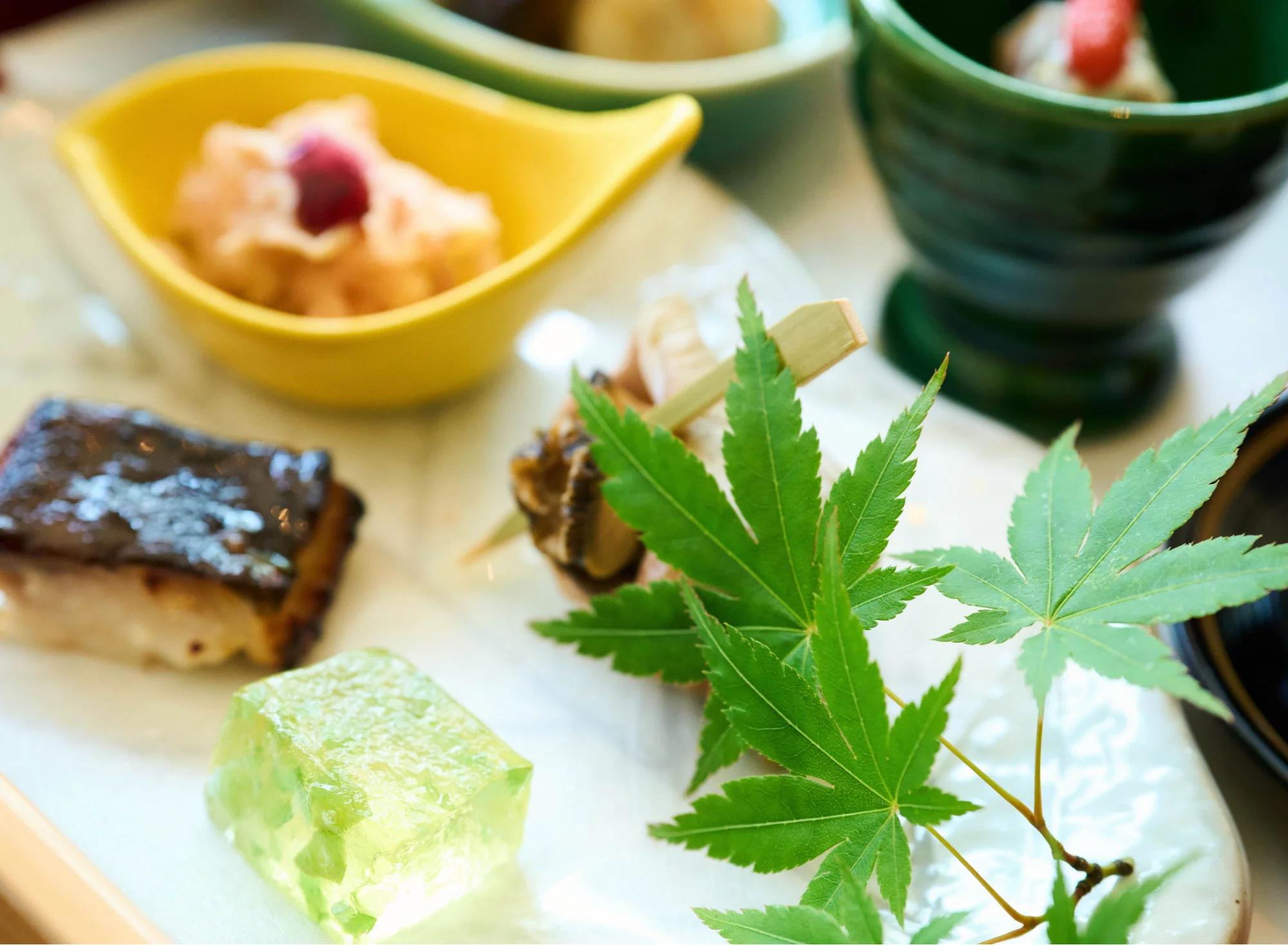 浅虫温泉 椿館の夕食膳「椿の箱」。青もみじが添えられた彩り豊かな小鉢や、職人の手仕事が光る繊細な前菜の数々