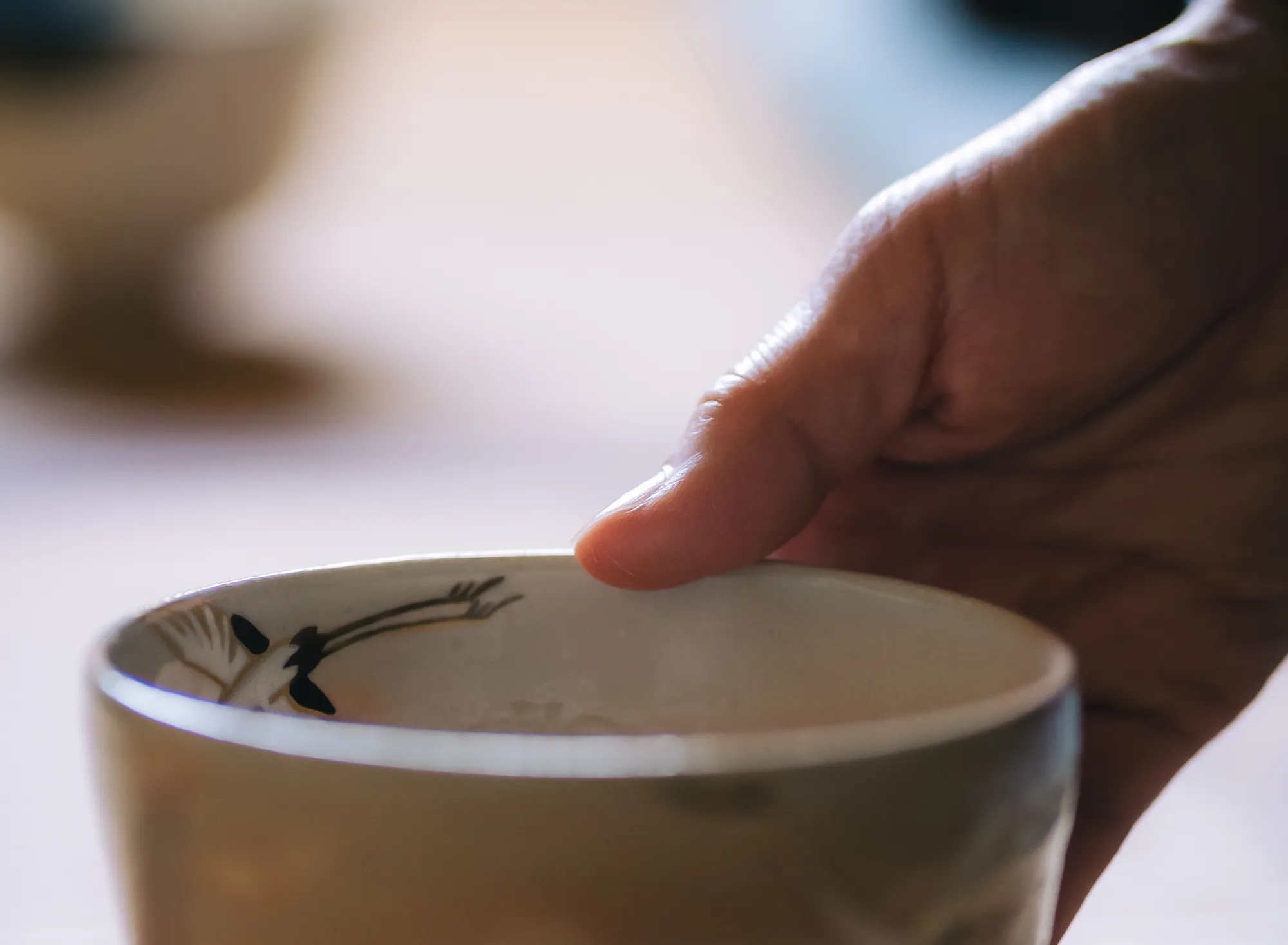 浅虫温泉 椿館の茶道体験。鶴の意匠が施された茶碗を手に取り、その質感と温もりを慈しむ瞬間。静寂の中で器の美しさに触れ、五感を通じて感性をひらく穏やかなひととき
