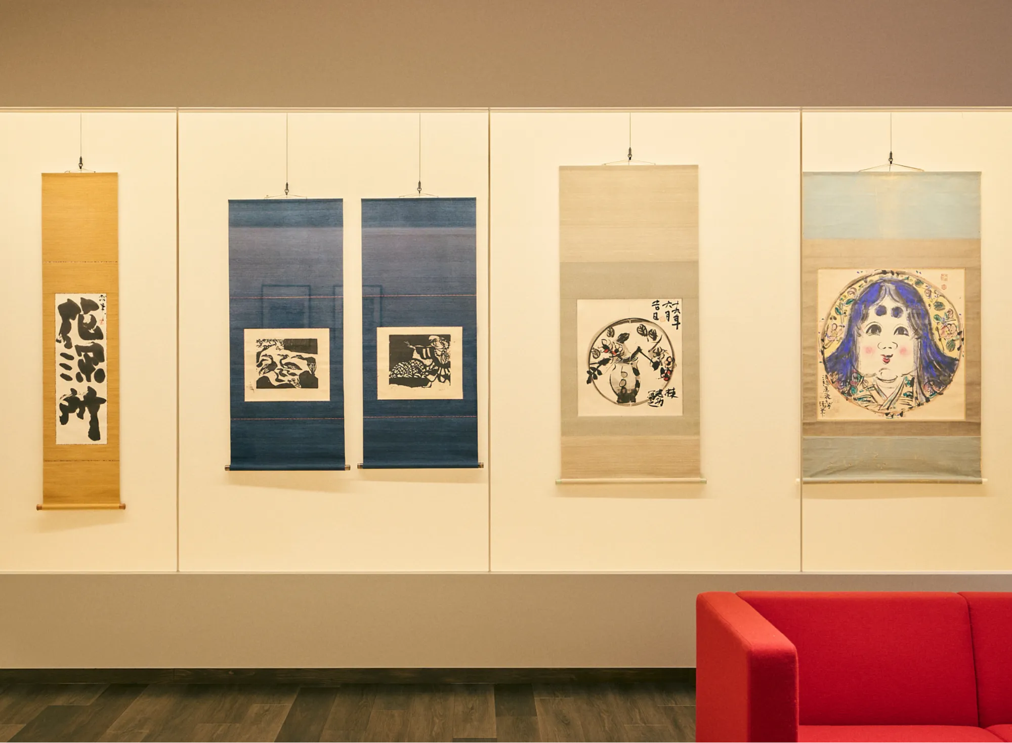 カルーセルの5枚目ですね。 志功画伯の多様な表現が一堂に会する、非常にバランスの良いカットです。 この画像は、画伯が手がけた**「板画（版画）」「倭画（肉筆画）」「書」という異なるジャンルの作品が、すべて「掛け軸」**として美しく仕立てられている点に触れるのがSEOのポイントです。 おすすめの代替テキスト（Altテキスト） 浅虫温泉 椿館の棟方志功ギャラリーに並ぶ掛け軸。力強い書、モノクロの板画、色彩豊かな倭画など、画伯の多彩な芸術に触れる展示コーナー