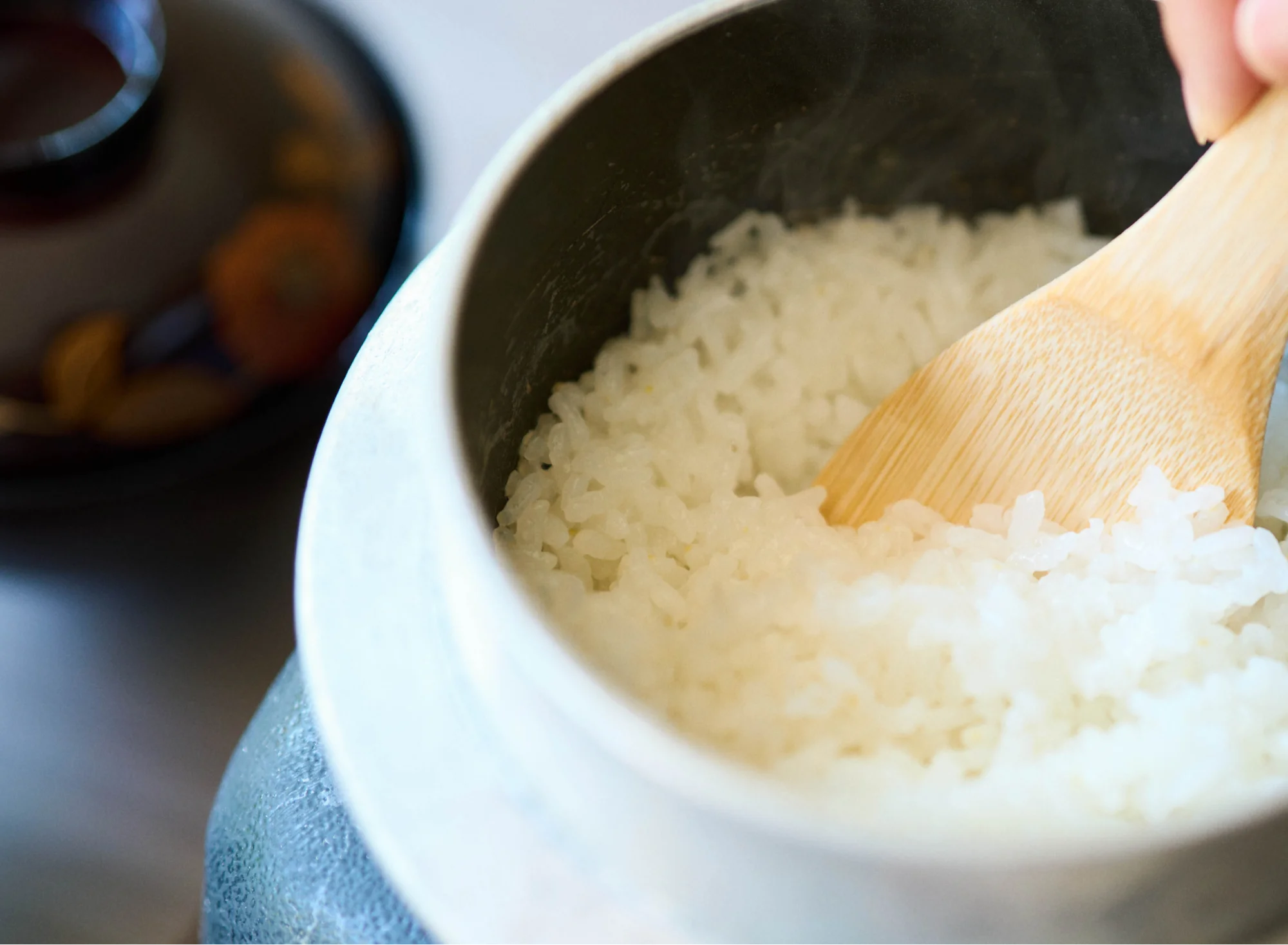 浅虫温泉 椿館の朝食。一人用の釜で炊き上げた青森県産米「あさゆき」と「はれわたり」の炊き立てご飯を、しゃもじでふっくらとほぐす様子