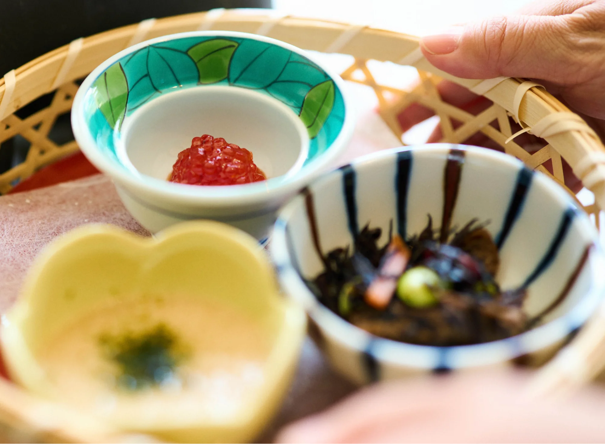 浅虫温泉 椿館の朝食。竹籠に盛り付けられた青森のソウルフード「すじこ」や地元の滋味豊かな小鉢など、津軽らしいご飯のお供の数々