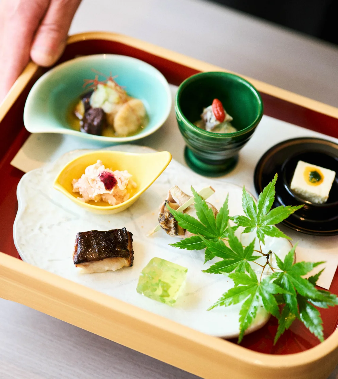 浅虫温泉 椿館の夕食膳「椿の箱」。青もみじが添えられた彩り豊かな小鉢や、職人の手仕事が光る繊細な前菜の数々