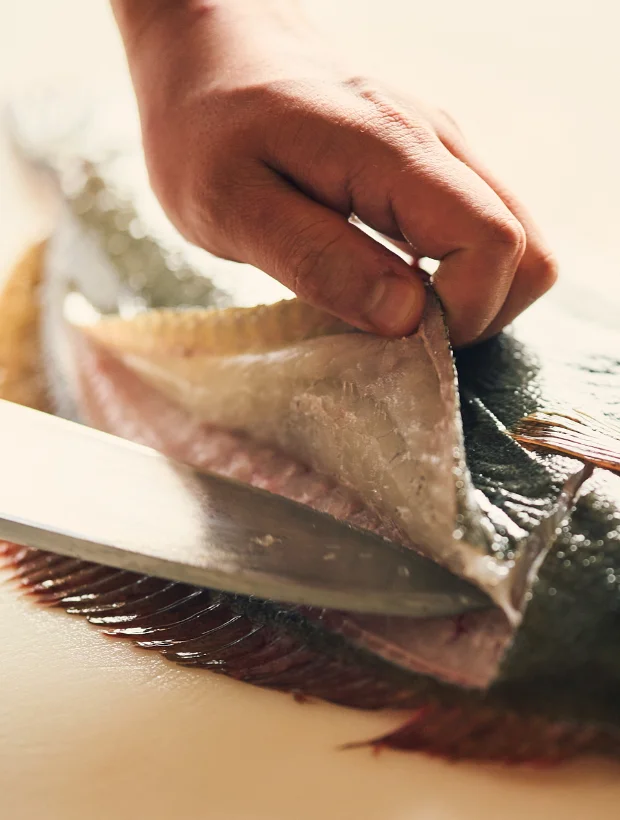 浅虫温泉 椿館の料理人が、市場直送の新鮮な魚を丁寧に捌く様子。鮮度と地産地消にこだわった夕食の仕込み風景