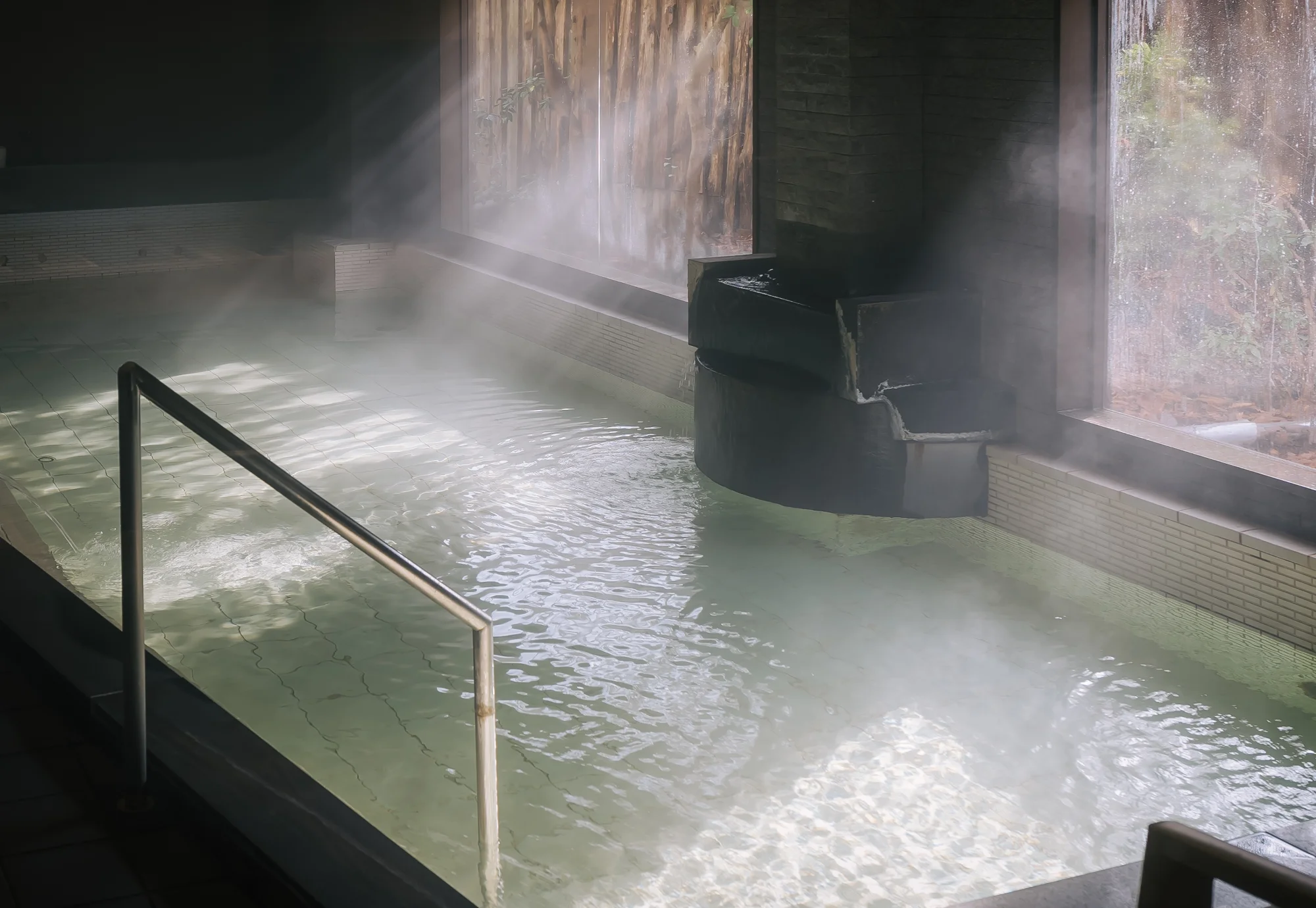 浅虫温泉 椿館の源泉掛け流し大浴場。大きな窓から光が差し込む幻想的な朝風呂の風景