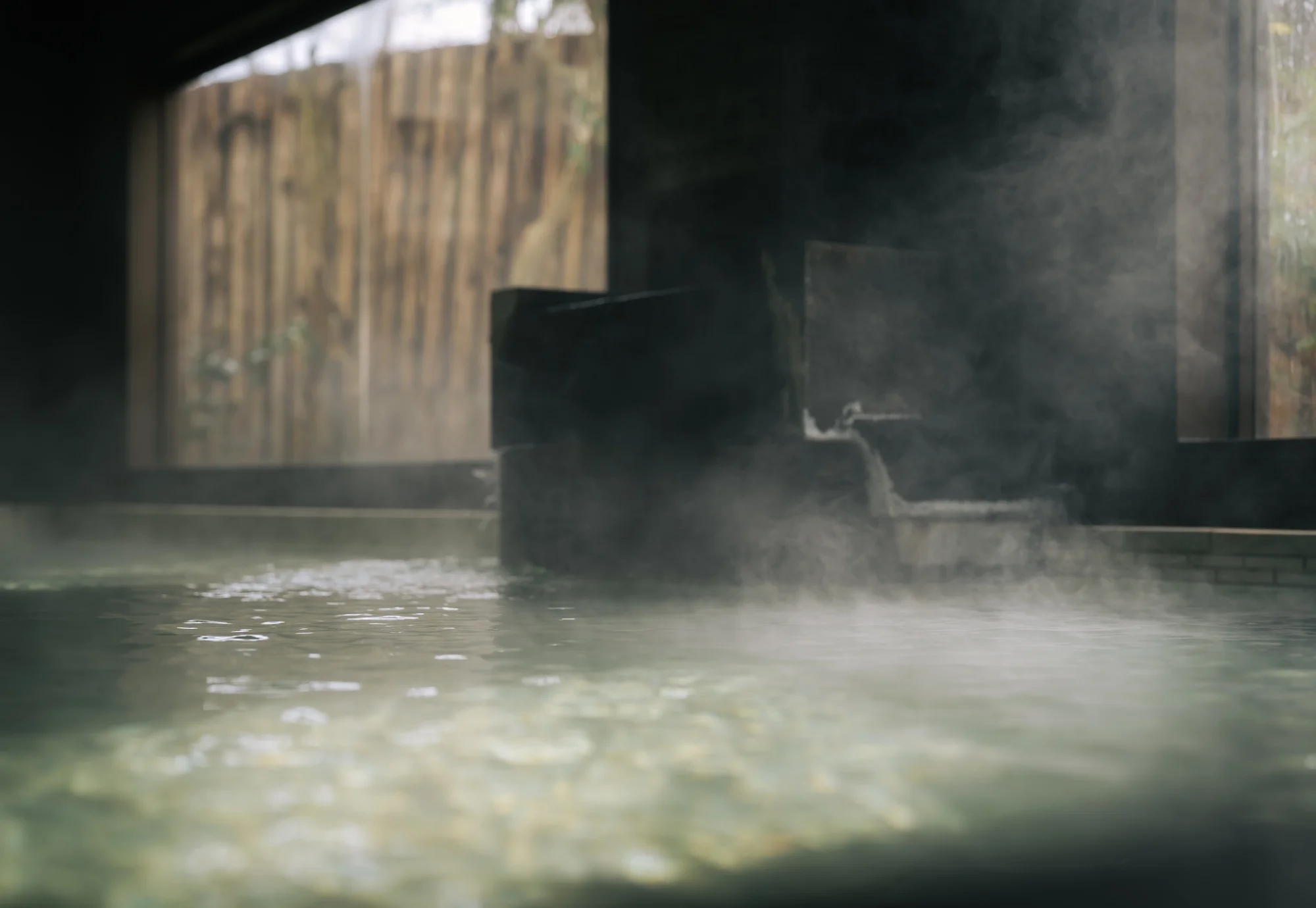 浅虫温泉 椿館の源泉かけ流し大浴場。湯口から注がれる豊かなお湯と、静かに立ちのぼる湯気に包まれる癒やしの空間