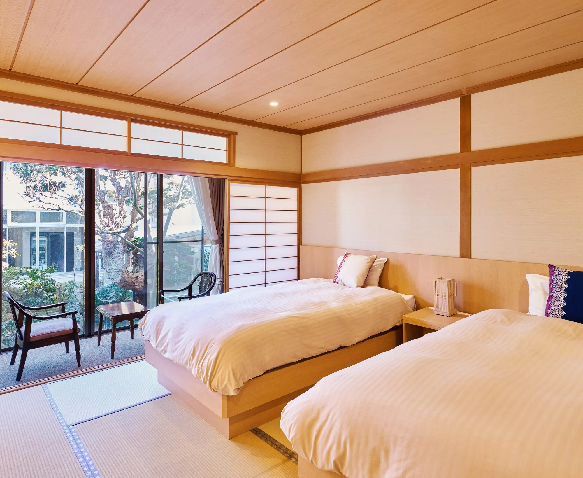 浅虫温泉 椿館「和室モダン（1F）」の客室。上質な眠りを提供するシモンズ製ベッドを完備した畳敷きの空間と、庭園を間近に望む広縁のテーブルセット