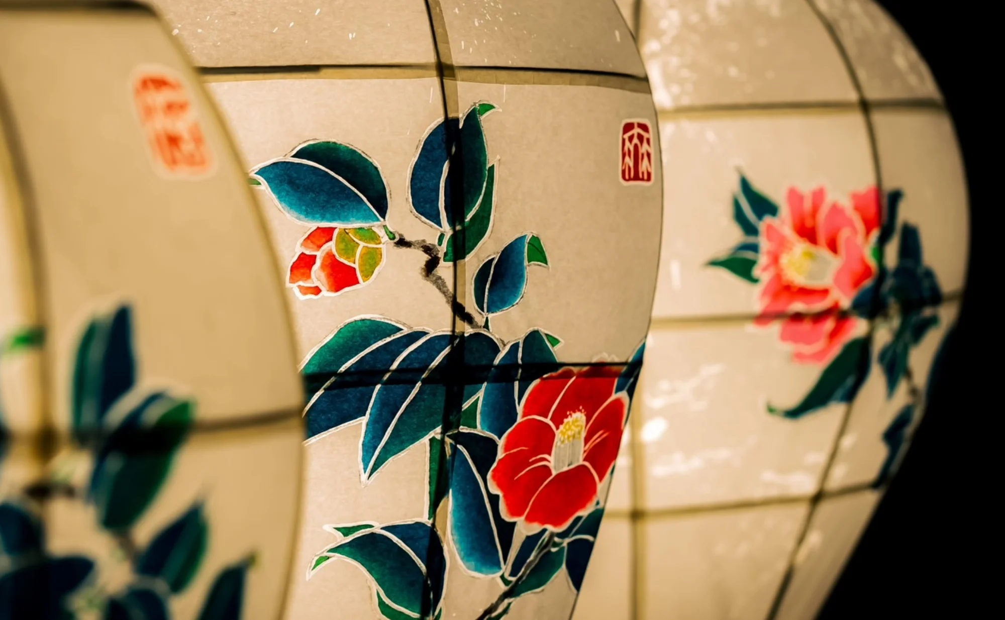 浅虫温泉 椿館の象徴である「椿」が描かれた、色鮮やかな灯籠。青森の伝統的な色彩感覚を彷彿とさせる力強い絵付けと、和紙を透かした柔らかな光。宿のルーツである椿の美しさを芸術的に表現し、訪れる人々を温かく迎え入れる椿館の伝統と感性が息づく一枚